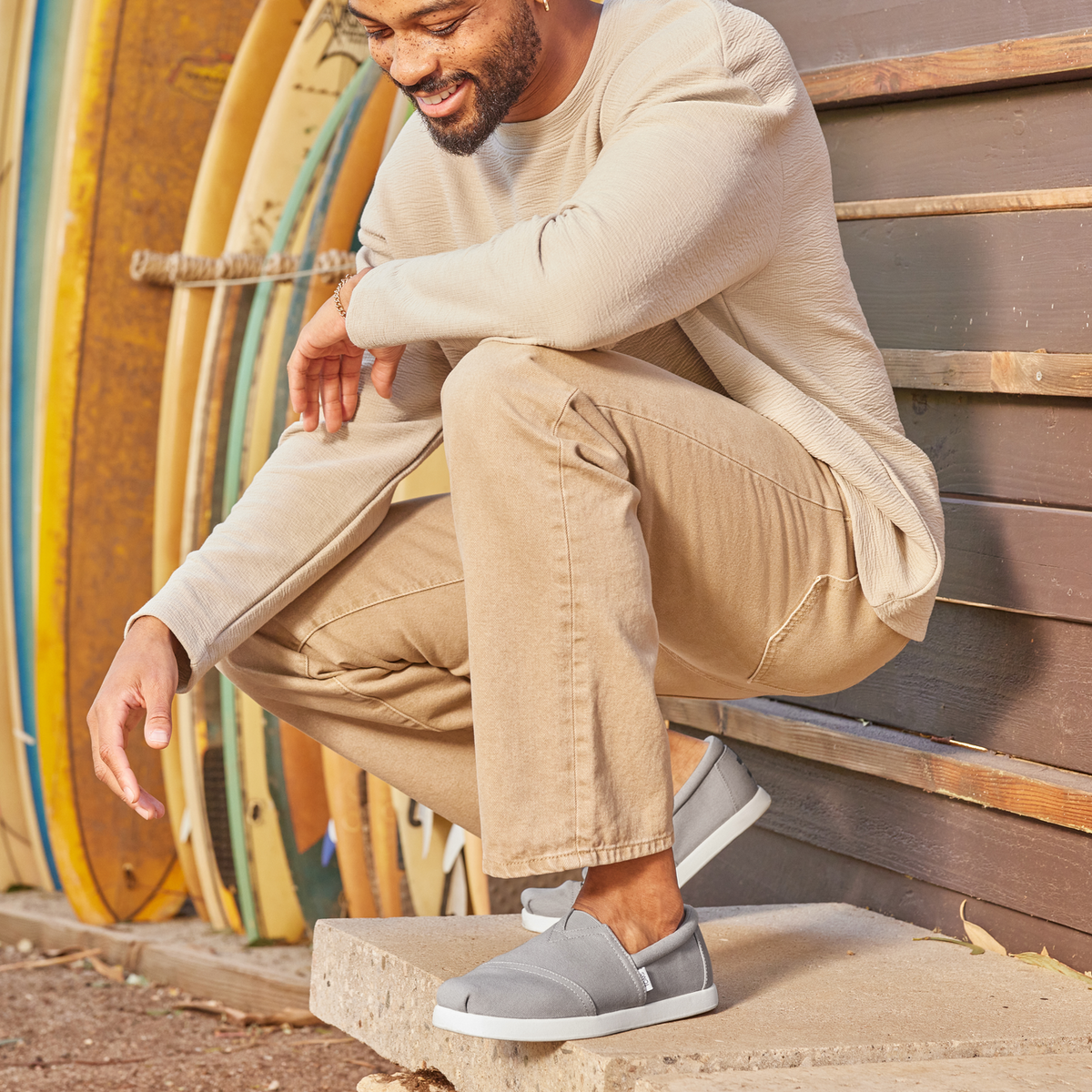 Mens Alpargata Fwd Slip On Casual Shoe In Grey On Model Squatting Next To Surf Boards